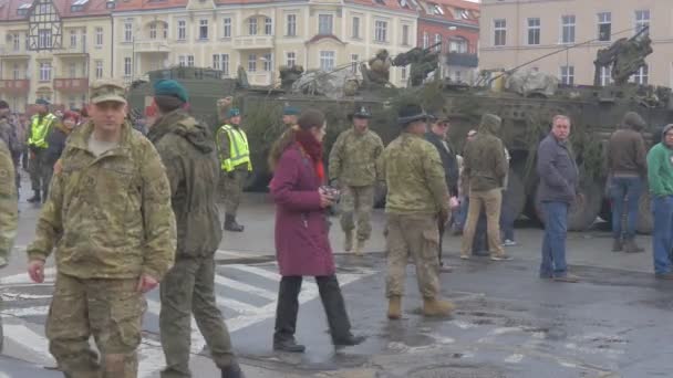 Żołnierze NATO w mundurze opolskie rozwiązują operację ludzie oglądają paradę chodzenie po placu miejskim stare budynki pojazdy wojskowe deszczowy dzień — Wideo stockowe