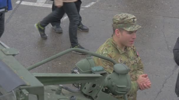 Soldado sorridente está conversando com pessoas Operação da OTAN em Opole Atlantic Resolver veículos militares na praça da cidade Pessoas estão assistindo ao desfile Dia Nublado — Vídeo de Stock