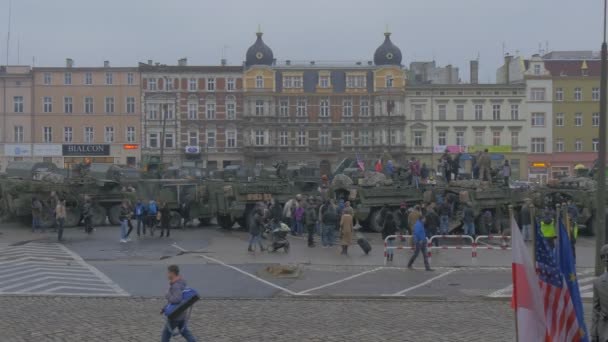 Пепе дивиться на парад операції НАТО в Ополе-Польщі солдати і військові машини прапори розмахуючи громадянами на міській площі старі будівлі похмурий день — стокове відео