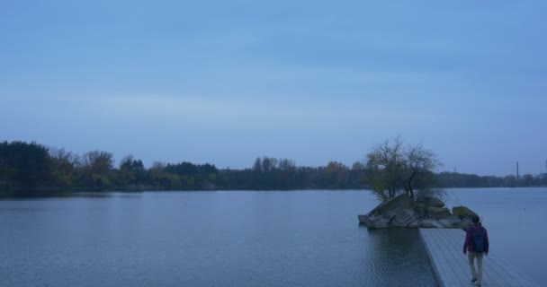 Promenades touristiques sur la jetée de béton Pierreux Petits arbres d'île envahis Paysage d'automne Arbres jaunes et verts sur le côté opposé Horizon Homme en soirée 