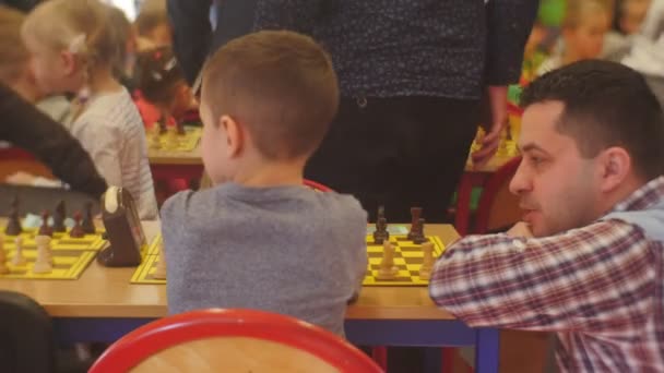 Kinderen en hun ouders op het schaaktoernooi "Black Knight" Club mensen lopen in de hal van de schaakclub strategie bordspel Opole Polen — Stockvideo