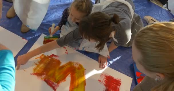 Enfants et éducateurs Peindre à la maternelle Animateurs Divertir les enfants Peintures colorées Photos Feuilles de papier colorées sur le sol Les gens qui enseignent aux enfants — Video