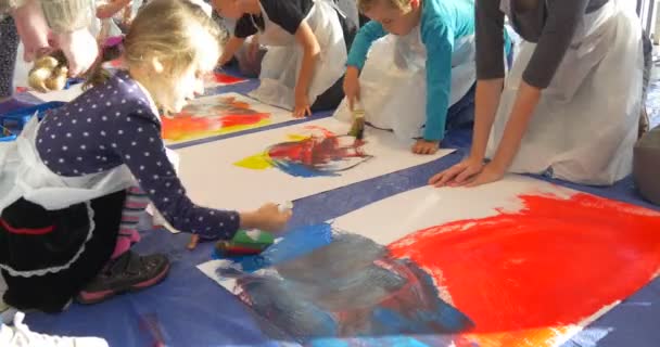 I bambini strisciano da grandi fogli di pittura su carta La gente dipinge nella scuola materna Educatori Bambini Animatori Intrattenere i bambini Pitture colorate Immagini Insegnamento — Video Stock