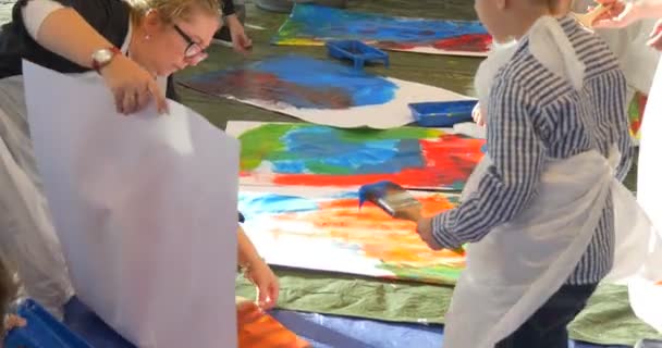 Les enseignants tiennent un plateau de peinture Les enfants peignent des photos à la maternelle Les éducateurs Les enfants animateurs divertissent les enfants Enseignement aux enfants Grandes feuilles de papier Photos — Video