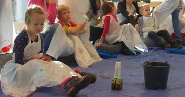 Familie Meisterklasse Opole Kinder sitzen auf einem Boden Malerei Galerie der modernen Kunst Menschen in Schürzen malen im Kindergarten Animatoren unterhalten die Kinder — Stockvideo
