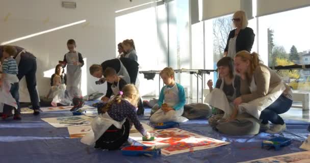 Famille Master Class Opole Les enfants écrivent leurs noms sur un papier sur un plancher Les parents regardent des gens souriants peindre à la maternelle Les éducateurs Familles ensemble — Video