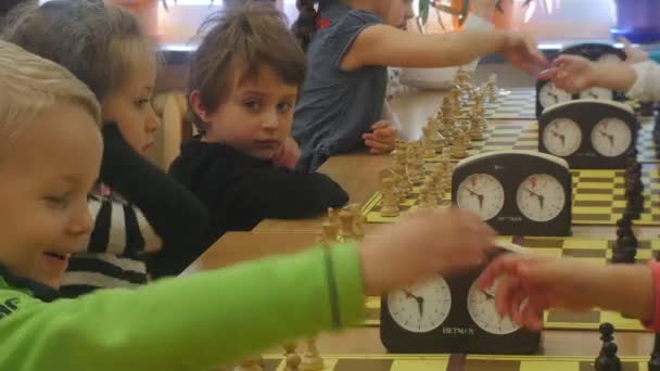 Torneo de Ajedrez "Caballero Negro" Club Kids se saludan con un apretón de manos el comienzo del juego de estrategia Elementos del tablero en las mesas — Vídeos de Stock