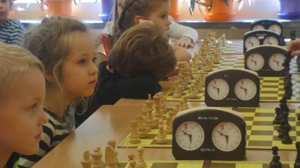 表坐在周围的小朋友们在国际象棋比赛组织"黑骑士"俱乐部孩子们正在玩象棋的棋盘游戏学龄前班奥波莱波兰 — 图库视频影像