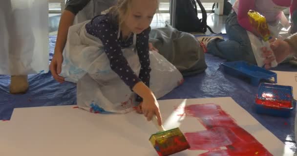 Crianças com mães estão pintando em papel na galeria de arte do assoalho Pessoas pintam no jardim de infância Educadores de sala de aula Animadores entretêm as crianças Famílias — Vídeo de Stock