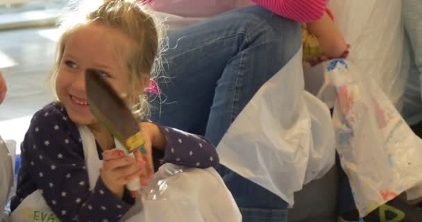 Kind Mädchen mit einem Pinsel lächelnd Menschen malen in Kunstgalerie Kindergarten Klassenzimmer Pädagogen und Kinder Animatoren unterhalten die Kinder Familien — Stockvideo