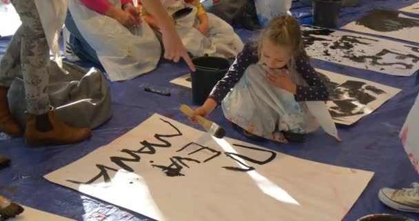 黒教育者が一緒に遊んでいる子供を助ける紙の絵に言葉を書いて家族マスター クラス美術館オポーレ子供子供の家族で楽しめる — ストック動画