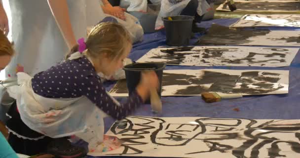 Niño pone un punto Pintura Negro en la galería de arte La gente se divierte Pintura en el jardín de infantes Educadores Animadores Entretener a los niños y las familias — Vídeos de Stock