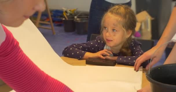 Οικογένεια Master Class Πινακοθήκη Opole Moms γυναίκες θέσει ένα φύλλα χαρτιού για το μικρό κορίτσι πίνακας είναι βλέποντας οι μαμάδες τα παιδιά πρόκειται να Paint βρώμικα χέρια και το πρόσωπο — Αρχείο Βίντεο