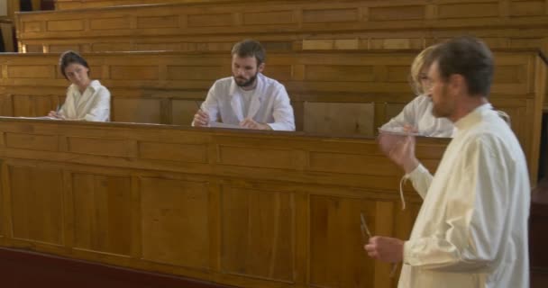 Professeur, chimiste, biologiste, enseignant tient la leçon devant les élèves, marche par auditorium, penché la main jusqu'au premier pupitre — Video