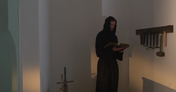 Mnich, muž s bradkou a knírkem v černých šatech, černá kápě, držící knihu, Nestor Kronikářovu knihu "příběh o dávno nekterých" — Stock video