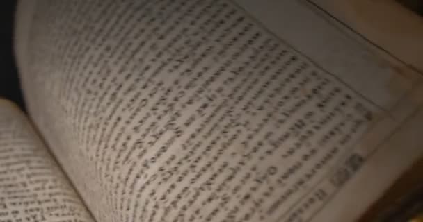 Человек в белых перчатках проникает сквозь "Старую книгу", прошивку, сценарий, буквы, страницы, луч света на книгу, тьму — стоковое видео