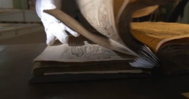 Biri beyaz eldiven Leafing aracılığıyla eski Holding kitap, arama, Resimler Closeup, Ray of Light üzerine kitabın karanlık sayfalarıyla kitap,