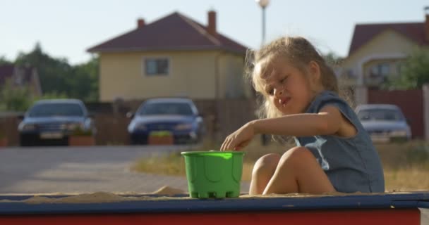 Ein kleines Mädchen spielt im Sandkasten — Stockvideo