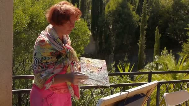Uma mulher de vestido brilhante desenha fotos em um terraço — Vídeo de Stock