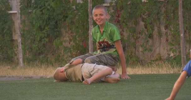 Jungen, Kinder, Kinder spielen auf einem Kinderspielplatz, liegen, rollen auf dem Gras, lachen, springen — Stockvideo