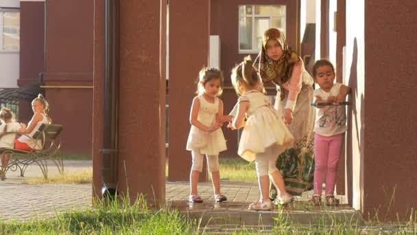 Frau im Hijab, Schal, geht mit Kindern spazieren, Kinder spielen auf einem Kinderspielplatz, zwei Mädchen-Zwillinge, Kinder waschen sich die Hände — Stockvideo