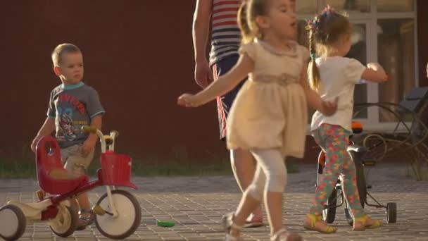 Дітей, дітей на дитячому майданчику, двір, ігрового, біг, велосипед, Tricycle, тато, батько є провідні велосипеда — стокове відео