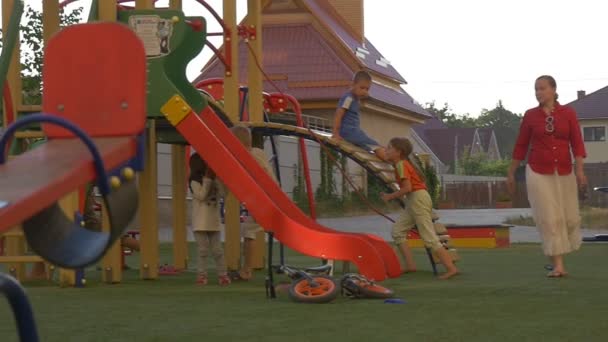 As crianças correm uma após a outra no parque infantil no quintal — Vídeo de Stock