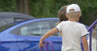 Parkında oynayan çocuklar, çocuklar, kız mavi oluğu, tırmanma merdiveni, pembe tişört, kız çocuk beyaz şapkalı, arabalar oynuyor