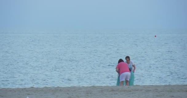 Люди, дети, семьи на песчаном пляже, люди покидают пляж, мамы заворачивают своих детей в полотенца после купания — стоковое видео