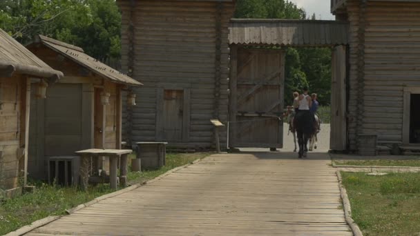 Троє вершників, вершників, їдуть через стародавні міські ворота, повільний рух — стокове відео