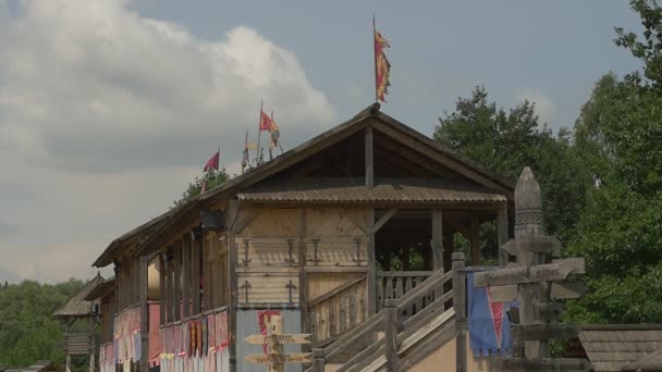 Drewniany budynek obserwacji z flagami w pobliżu stadionu, drogowskaz, drogowskaz, drzewa — Wideo stockowe