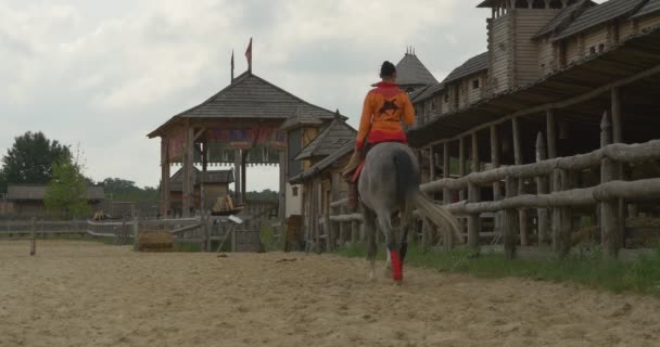 Os atores nos cavalos estão montando para o estábulo, estádio, edifícios de madeira — Vídeo de Stock