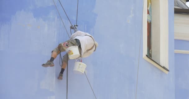Restaurátor, člověče, průmyslové lezce na zdi, malovat v prodlení, sedící na sedadle drží na laně, katedrála St. Michael, opravy — Stock video