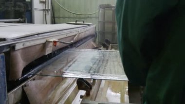 Turuncu Kasklı ve Üniformalı İşçi Cam Sayfayı Öğütme Makinesine, Oda Makinesine, Oda Yapım Odası 'na ve Su' ya koyuyor.