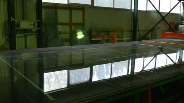Drie werknemers in oranje veiligheidshelmen, snijden robot, inzoomen, grote glazen blad close-up, snijden van blad glas door robot — Stockvideo