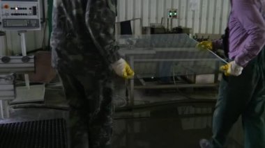 Üniforma ve turuncu Emanet kask, sarı eldivenler, aldı iki işçi cam levha standından, makineye koymak