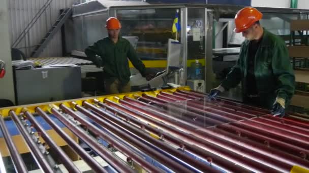 Dua pekerja di Orange Safety Helmets, Man is Wiping the Sheet of Glass, Sheet of Glass is Moving to The Oven, To The Machine — Stok Video