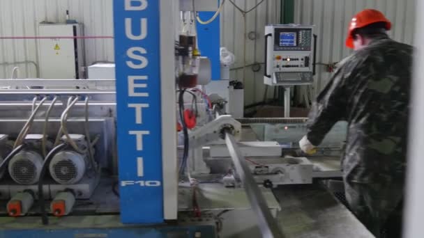 Dos trabajadores en cascos de seguridad naranja están poniendo la hoja de vidrio en la máquina de pulir, pulido con agua, primer plano de la máquina — Vídeos de Stock