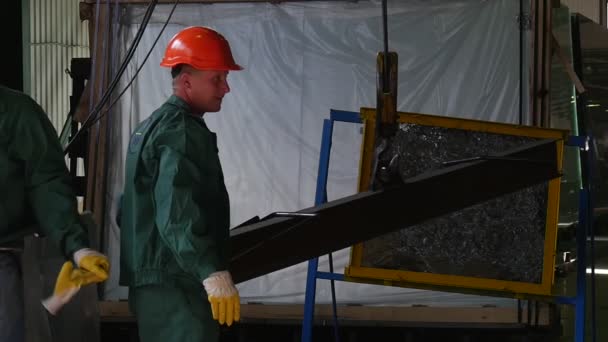 Два рабочих в униформе и оранжевых защитных шлемах стоят у испытанного стекла, разбитого стекла, тарана в цепи, человек в гражданской одежде — стоковое видео