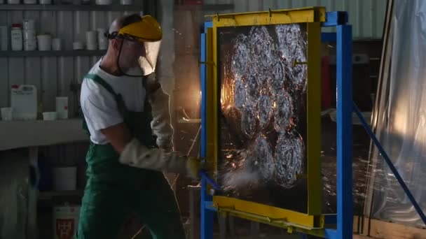 Trabajador en uniforme y pantalla protectora está golpeando la hoja de vidrio con Hummer pequeño, Hoja de vidrio está en marco de metal, Pruebas de vidrio a prueba de balas — Vídeo de stock