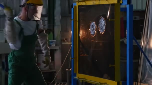 Работник в форме и защитный экран бьет гладкий лист стекла с маленьким Хаммером, делая круглые трещины, испытания пуленепробиваемого стекла — стоковое видео
