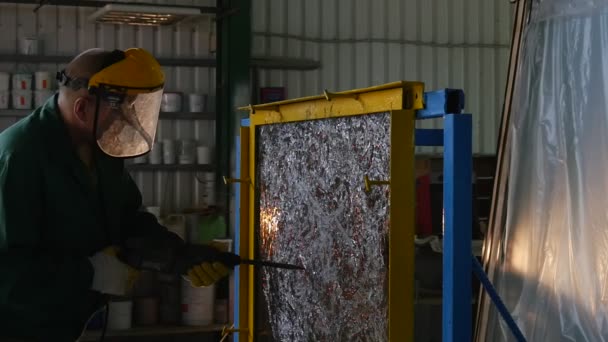 Lavoratore in uniforme e schermo protettivo sta perforando la lastra di vetro da Puncher, lastra di vetro è in telaio in metallo, stand, crepe sul vetro — Video Stock