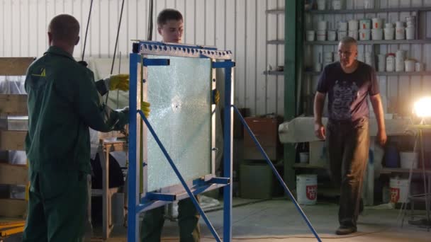 Arbeiter lösen die Schrauben des Metallrahmens, ersetzen das geprüfte Glas, Glas mit Loch, Prüfung von Panzerglas, gehärtetem Glas — Stockvideo