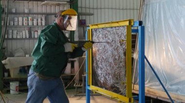 İşçi üniforma, koruyucu ekran ve sarı eldivenler, temperli cam levha zımba ile sondaj, cam levha çerçevede Stand