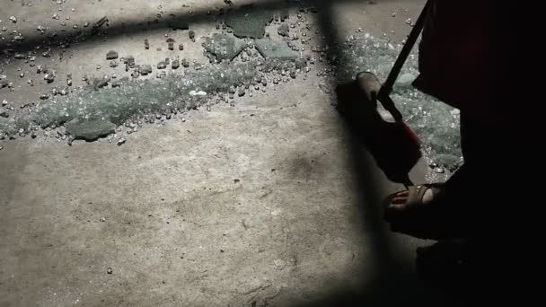 Trabalhador, silhueta, pés de perto, está varrendo o chão, varrendo vidro quebrado, vidro quebrado, quarto escuro, raio de luz, silhueta de grades — Vídeo de Stock