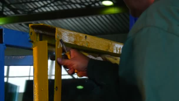 Deux travailleurs en uniforme détordent les boulons dans un cadre métallique, la feuille de verre lisse est dans le cadre, avant le test, logo d'usine sur la veste du travailleur — Video