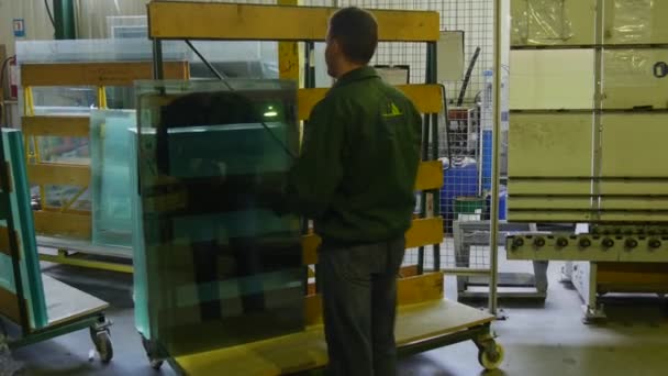 Trabajador en uniforme de fábrica verde está de pie en el stand con vidrio, mirando el vidrio, caminando lejos, logotipo de la fábrica está en la chaqueta — Vídeo de stock