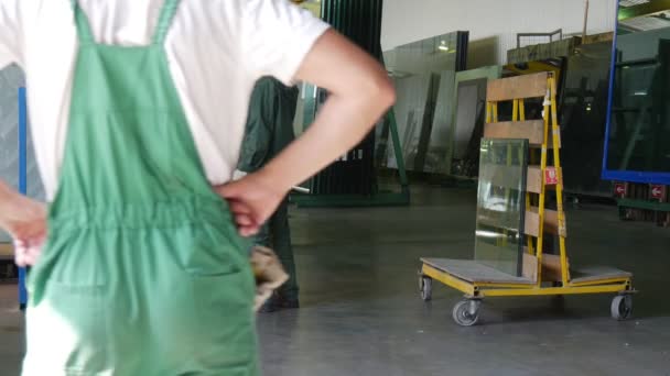 Quattro operai e l'uomo in civile stanno levandosi in piedi alla struttura del metallo, prima della prova di vetro, logo della fabbrica è sulla giacca del lavoratore — Video Stock