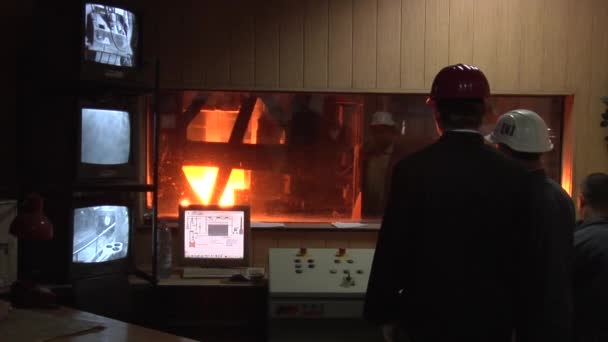 通过窗口的高炉三名工人正在通过窗口观察过程，并筛选工人在安全头盔男子的背部 — 图库视频影像