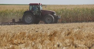 Adam Pulluk ile Sağa Sürülen TraktörÜ Sürüyor Toprak Bitkileri FonLa Arka Plan Horizon Mavi Gökyüzü'nde Tarlada Büyüyor